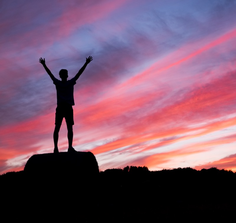 Personne bras levés au coucher du soleil - formation confiance en soi – coaching gestion du stress – Audrey Martin Coaching