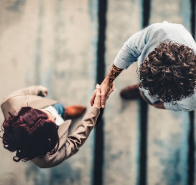Poignée de main vue du dessus, symbolisant la communication non violente, formation soft skills entreprise – Audrey Martin Coaching